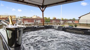 A hot tub with a metal bucket containing a bottle of champagne, surrounded by outdoor furniture. - Hotel Bishops Arms Strangnas (Strängnäs)