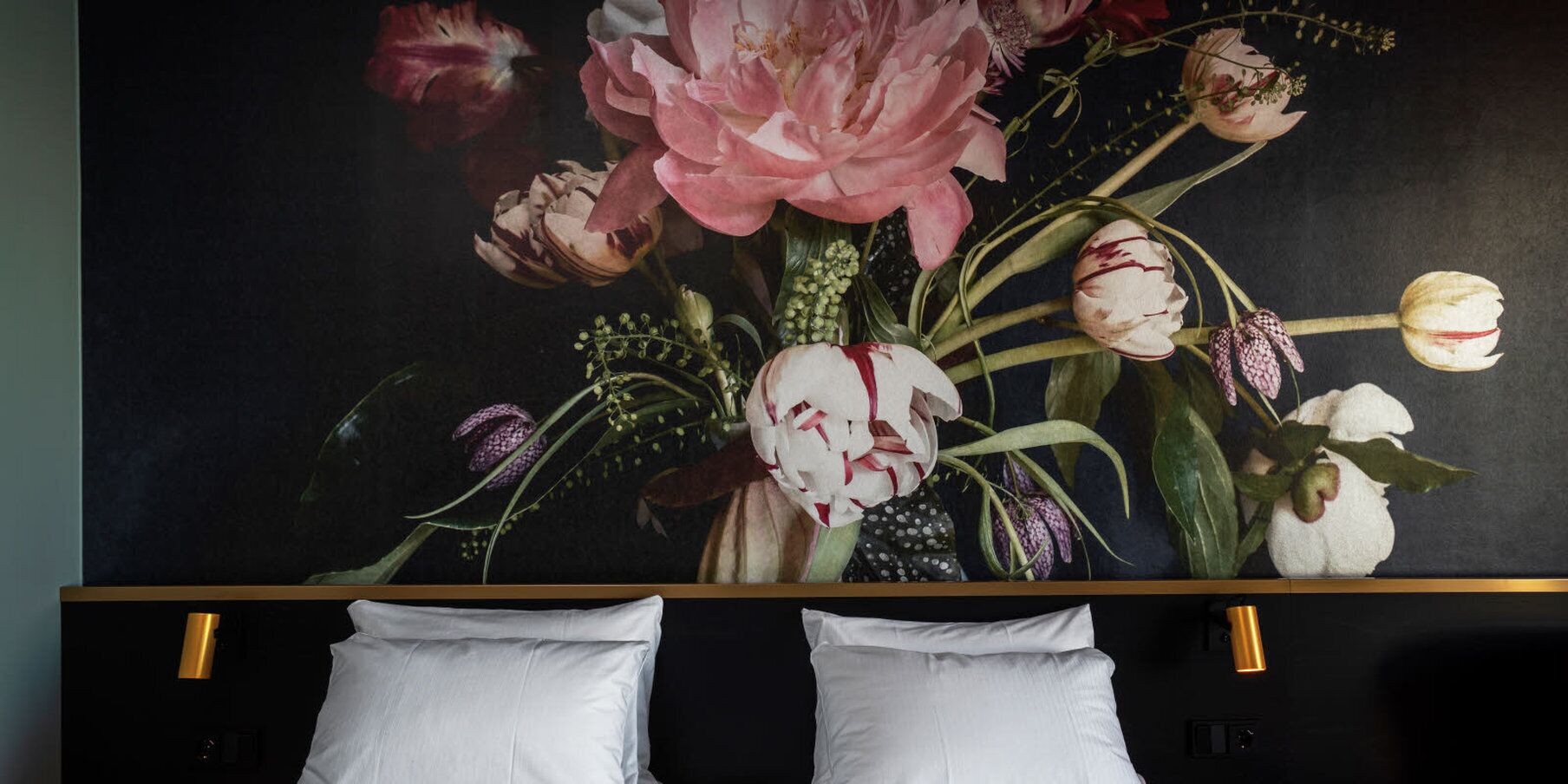 A wall with a floral painting and two white pillows.