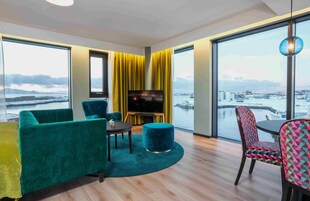 Una habitación moderna con un ventanal grande, un sofá, un televisor y una silla.