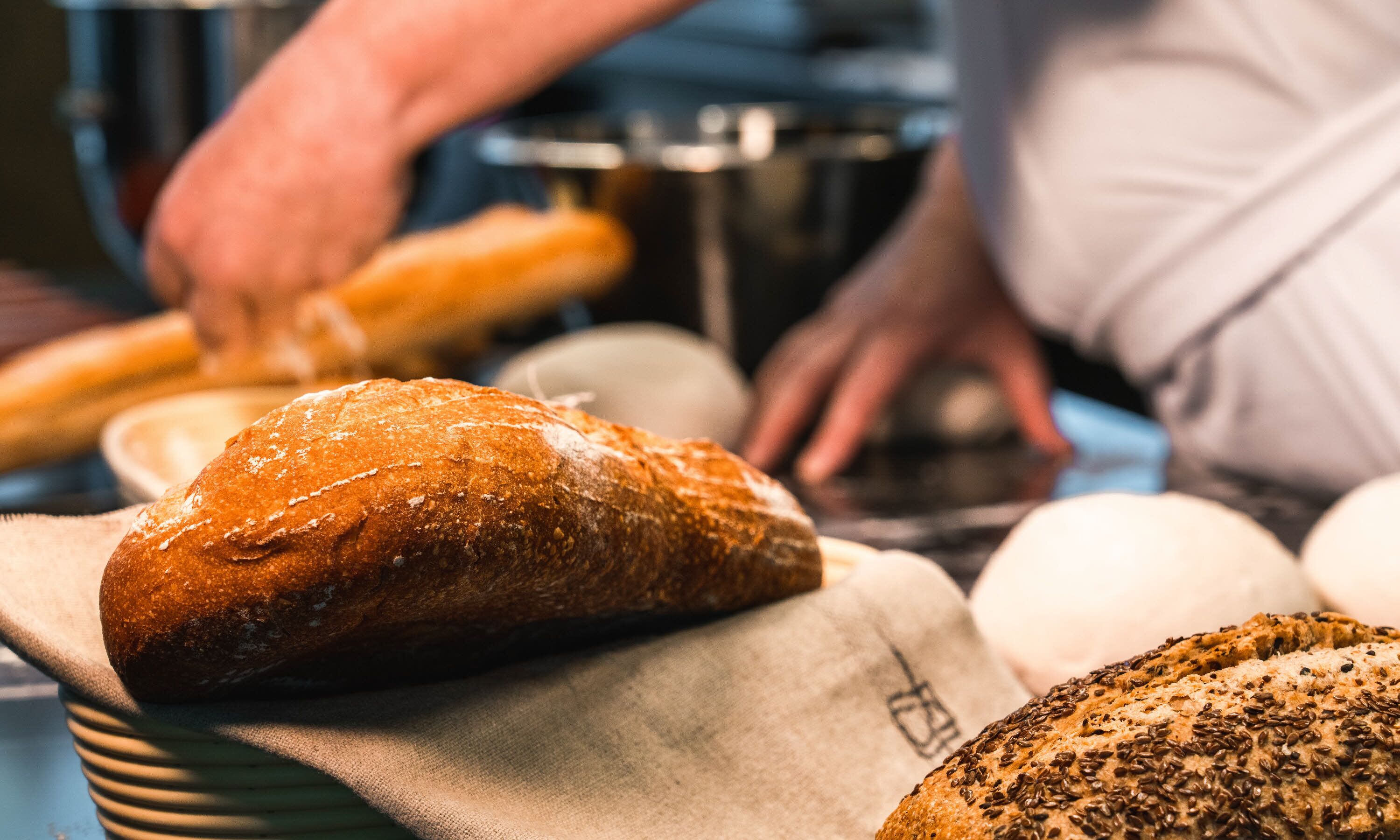 A variety of breads on a table, including a loaf with seeds on top.