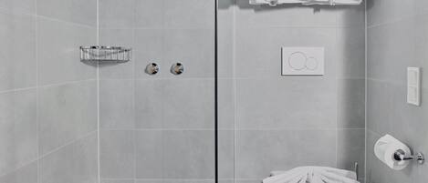 Une salle de bain moderne avec des carreaux gris, des toilettes, un lavabo avec un porte-serviettes et un espace douche.