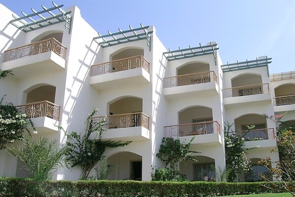 Un hotel de varios pisos con balcones, ventanas arqueadas y un cielo despejado.