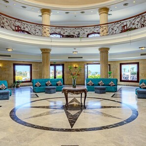 A lobby with a central round table, sofas, and large windows.