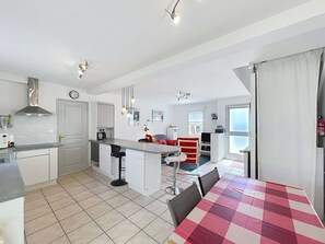 A compact kitchen with a dining area, a visible clock, and a window. - Quiberon - 4 rooms house - 77m² - quiet area (QUIBERON)