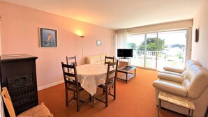 A living room with a dining table, chairs, a sofa, a TV, and a balcony with a view. - Quiberon - 2 rooms appartment - 56m² - near beach (QUIBERON)