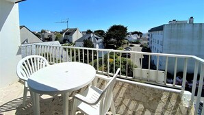A balcony with a white table and chairs, overlooking a residential area with houses and a crane in the distance. - Quiberon - 2 rooms appartment - 56m² - near beach (QUIBERON)