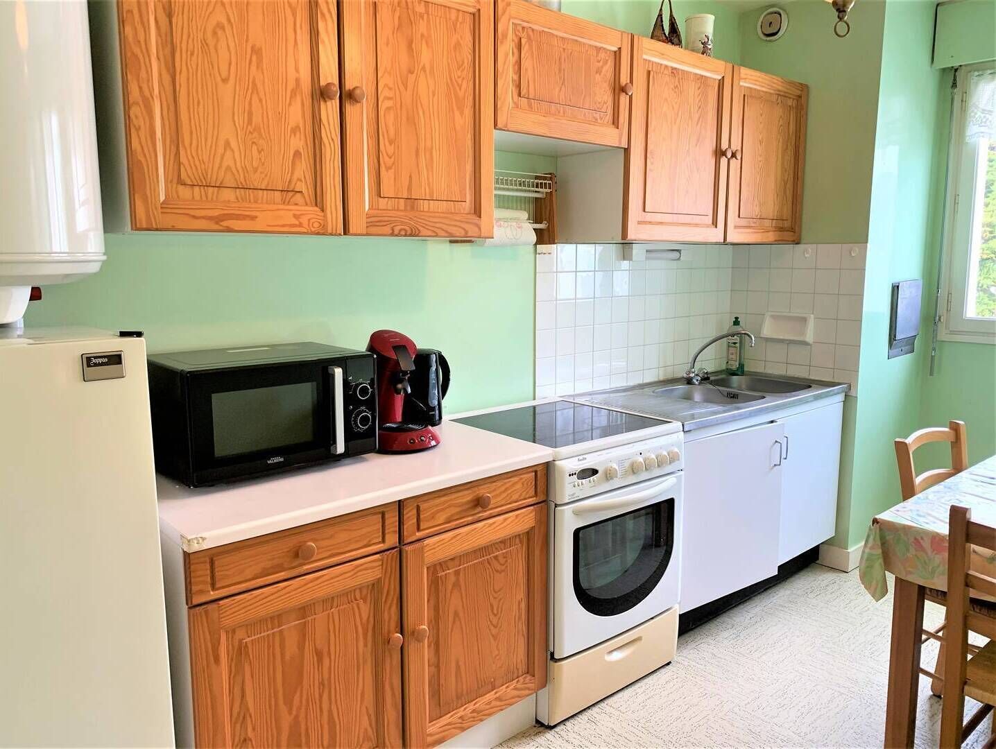 A compact kitchen with wooden cabinets, a microwave, a coffee maker, a sink, and a stove.