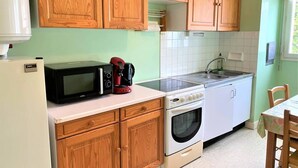 A compact kitchen with wooden cabinets, a microwave, a coffee maker, a sink, and a stove. - Quiberon - 2 rooms appartment - 56m² - near beach (QUIBERON)