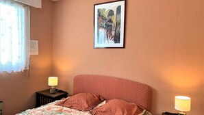 A bedroom with a bed, two bedside tables with lamps, a framed picture on the wall, and a window with a curtain. - Quiberon - 2 rooms appartment - 56m² - near beach (QUIBERON)
