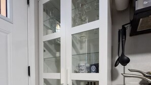 Eine Küche mit einem weißen Schrank, der Gläser, eine Kaffeemaschine und Küchenutensilien beherbergt.