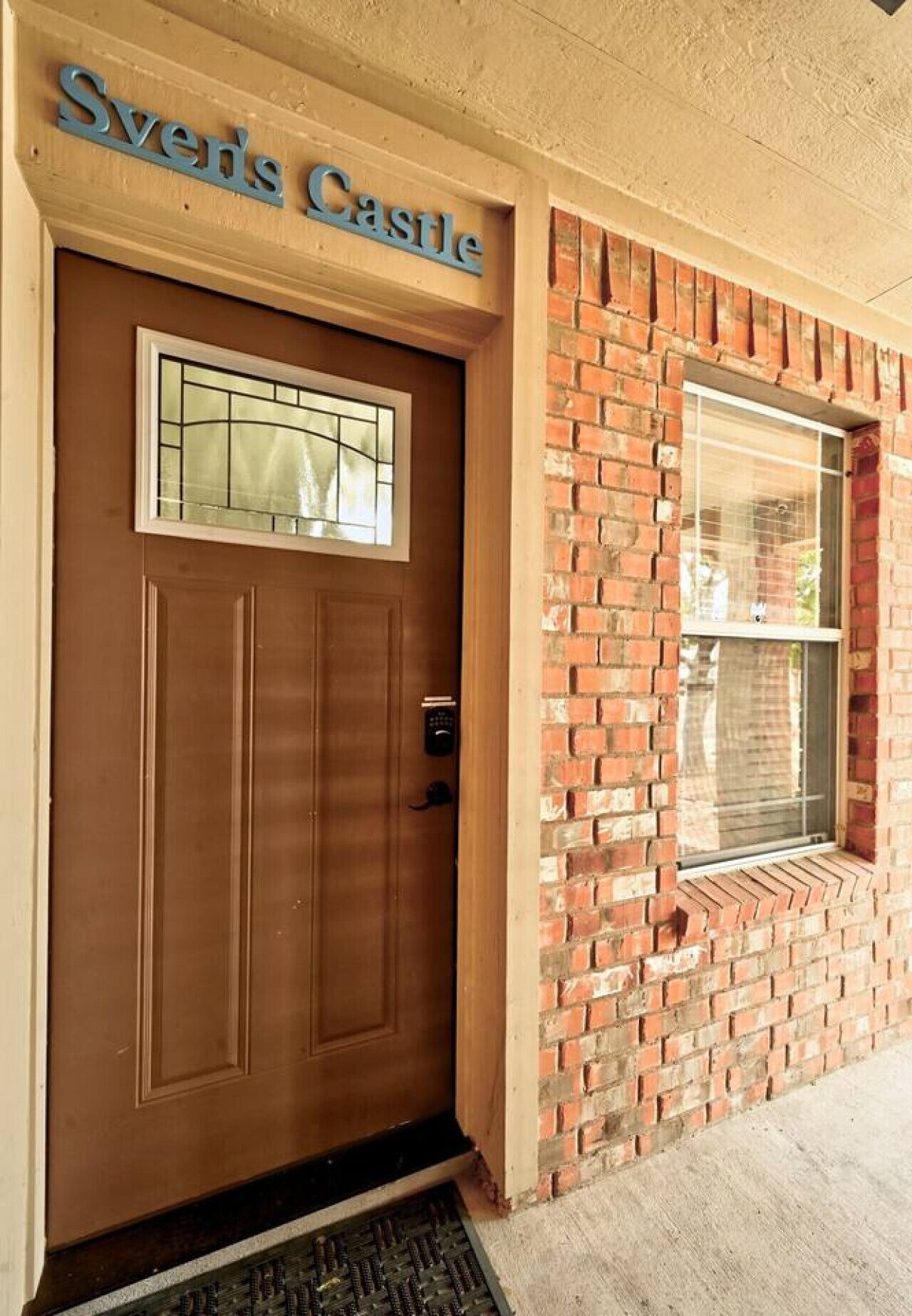 A brown door with a window above it and a sign above the door that reads "Sver's Castle".
