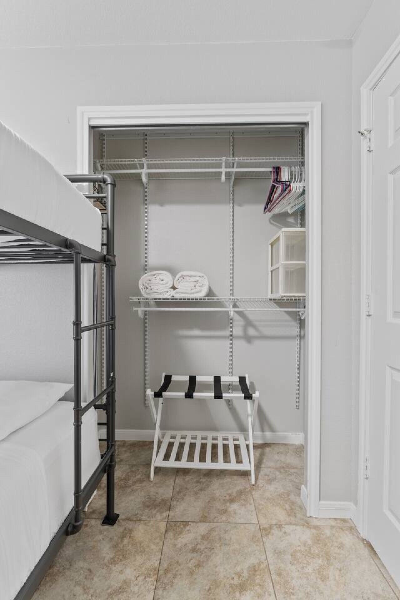 A walk-in closet with metal shelving, a white bench, and neatly folded towels.