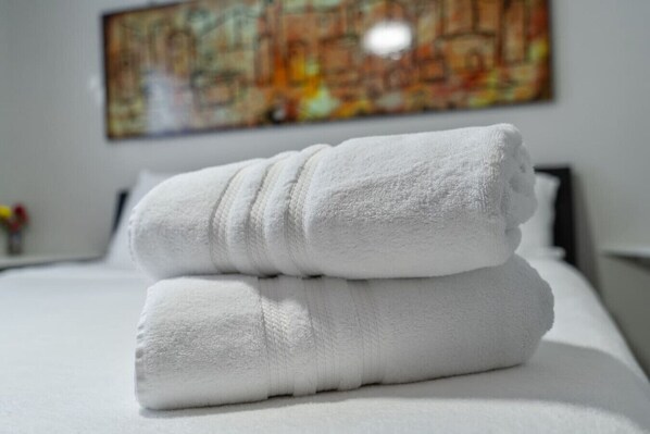 A neatly made bed with two folded white towels on top.