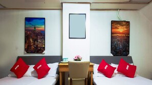 Habitación de hotel con dos camas, cada una con almohadas rojas y vistas a la ciudad.