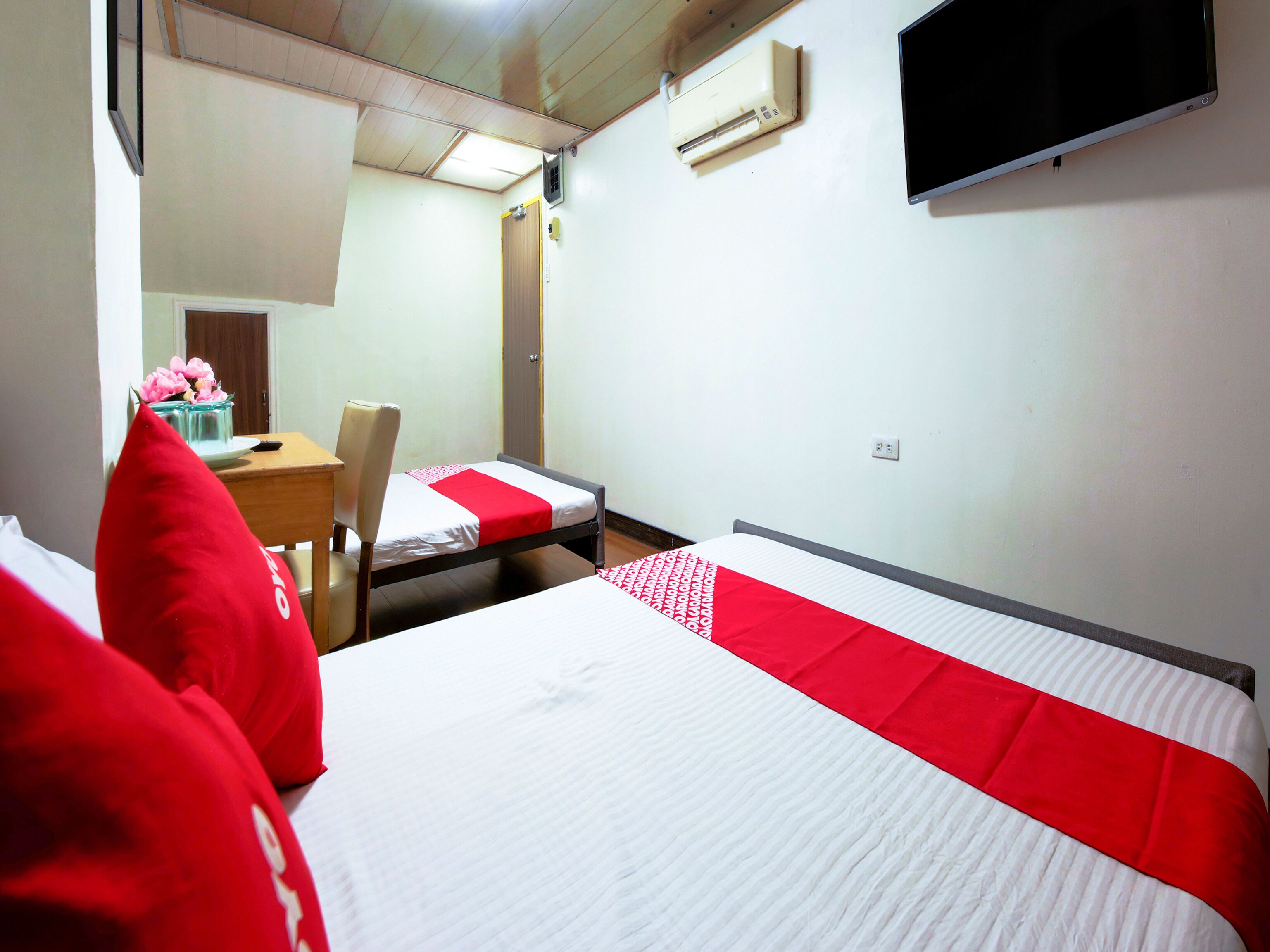 Ein Hotelzimmer mit Bett, Schreibtisch, Stuhl, Fernseher und Klimaanlage.