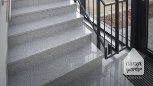 Un escalier avec une rampe en métal menant à une porte dotée de panneaux de verre.