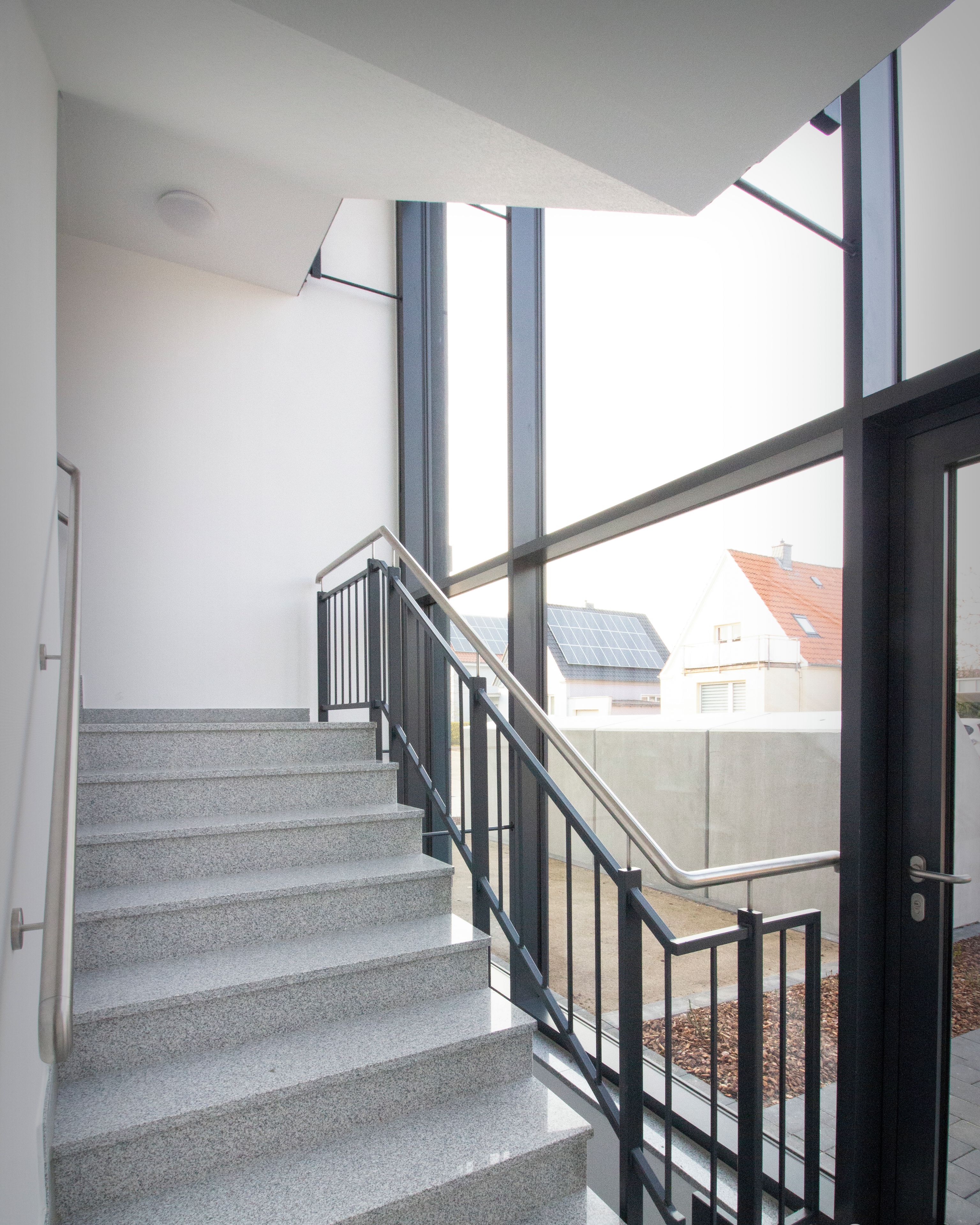 Un escalier avec une rampe en métal menant à une porte dotée de panneaux de verre.