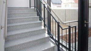 Un escalier avec une rampe en métal menant à une porte dotée de panneaux de verre.