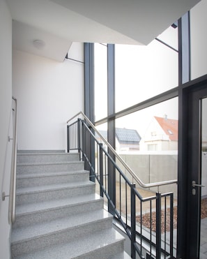 Un escalier avec une rampe en métal menant à une porte dotée de panneaux de verre.