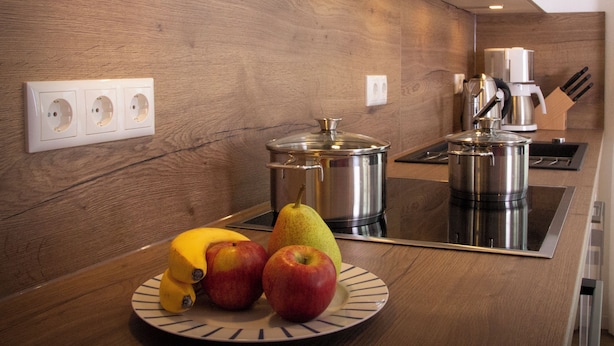 Une cuisine moderne avec des meubles en bois, une cuisinière en acier inoxydable et un panier de fruits posé sur le plan de travail.