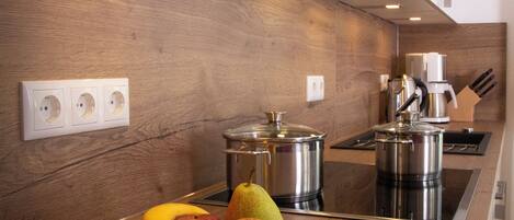Una cocina moderna con armarios de madera, una estufa de acero inoxidable y un frutero sobre la encimera.