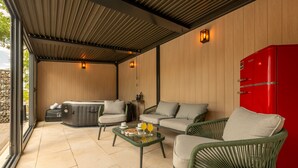 A covered outdoor seating area with a hot tub, sofas, and a red refrigerator. - Villa Zen Promona (Promina)