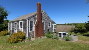 A two-story house with a chimney, a lawn, and a barbecue grill.