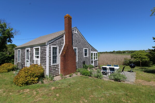 Une maison à deux étages avec une cheminée, une pelouse et un barbecue.