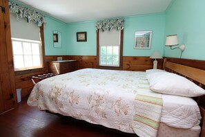 A bedroom with a bed, a dresser, a window, and a wall-mounted lamp.