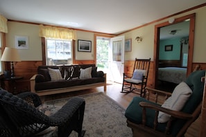 A cozy living room with a sofa, chairs, a rug, and a window with curtains.