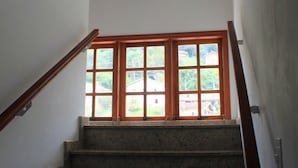 Una escalera con barandillas de madera que conduce a un rellano con un amplio ventanal.