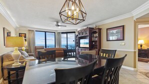A dining area with a glass table, dark chairs, a chandelier, and a view of the ocean. - Fantastic Rates! Gulf Front 3Br/2Ba*12th Floor*Phoenix X Unit 1213 (Orange Beach)