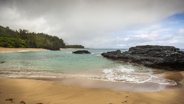 A beach with clear turquoise water, sandy shore, and rocky outcrops. - Air-conditioned, spacious, golf-front living (Princeville)