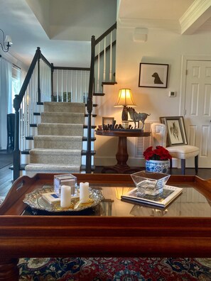 A staircase with a patterned carpet, a table with a tray, a lamp, and a framed picture of a dog.