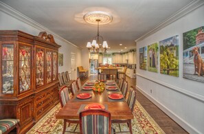 A formal dining room with a long wooden table, striped chairs, and a large wooden cabinet with glass doors.