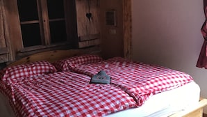 En træseng med et ternet sengetæppe og en hjerteformet pynt på væggen.