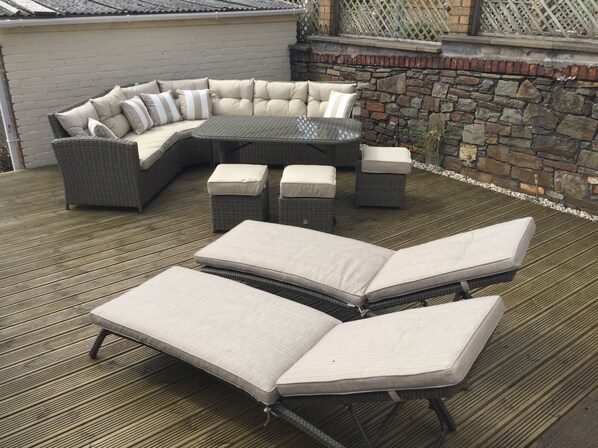 A patio with a sectional sofa, two chaise lounges, and a small table.