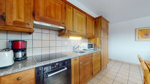 A kitchen with wooden cabinets, a stainless steel range hood, a microwave, a coffee maker, and a dishwasher.