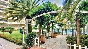 A courtyard with a pool, palm trees, and a white fence. - 2 ROOMS, IN LUXURY RESIDENCE, SWIMMING POOL, AIR CONDITIONING, BY THE SEA (Antibes)