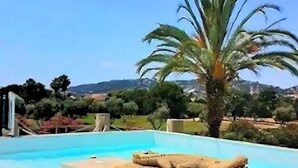 A swimming pool with a stone sculpture in the center, surrounded by greenery and a clear sky. - 2 ROOMS, IN LUXURY RESIDENCE, SWIMMING POOL, AIR CONDITIONING, BY THE SEA (Antibes)