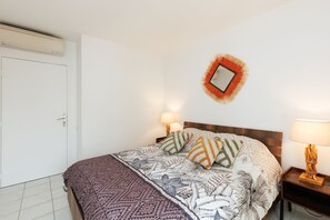 A bedroom with a bed, two bedside lamps, a wall-mounted mirror, and a door. - 2 BEDROOMS, IN A LUXURY RESIDENCE, SWIMMING POOL, AIR CONDITIONING, BY THE SEA (Antibes)