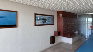 A modern interior with a geometric ceiling, a framed landscape painting, a row of lockers, and a blue carpeted area.