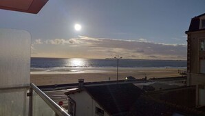 Vista a la playa desde un balcón, con una señal de stop, una farola y la costa al fondo.