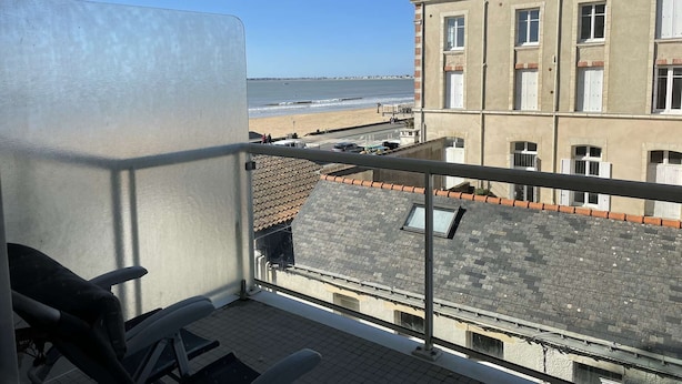 Un balcón con vista a la playa y un edificio al otro lado de la calle.