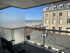 Un balcon avec vue sur la plage et un immeuble situé de l’autre côté de la rue.