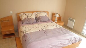 Une chambre à coucher avec un lit, des tables de chevet, une lampe et un radiateur.
