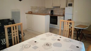Une cuisine de taille réduite avec des meubles blancs, une petite table à manger et une seule chaise.
