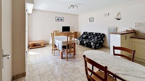 Un coin repas comprenant une table et des chaises, un canapé, un petit banc et un coin cuisine.