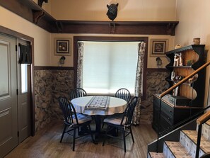 A dining area with a stone wall, a round table, and black chairs. - Mountain retreat with close proximity to lake and town square (Prescott)