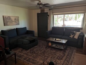 A living room with a dark-colored sofa, a coffee table, a rug, and a painting on the wall. - Mountain retreat with close proximity to lake and town square (Prescott)